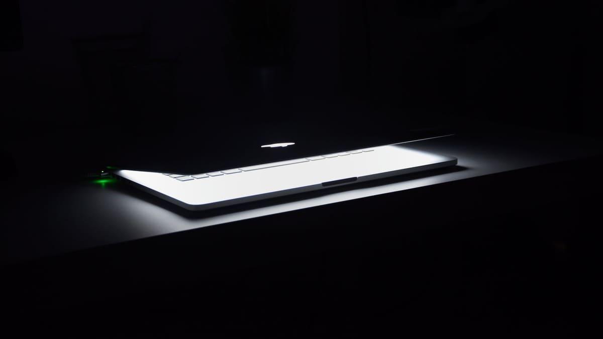 Closed laptop on an empty desk in a dimly lit room