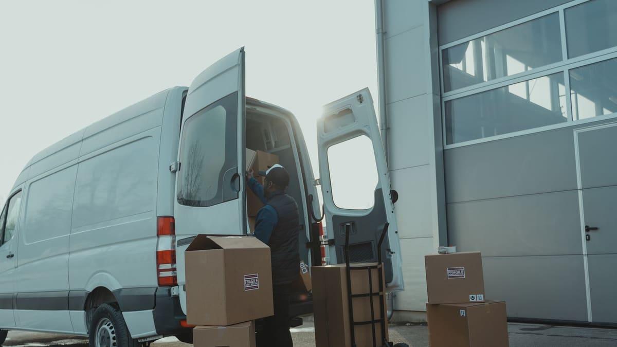 Delivery driver loading parcels into a van early in the morning